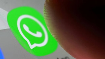 Primer plano del logo verde de WhatsApp en una pantalla digital, con una parte de un dedo humano visible en el lado derecho de la imagen