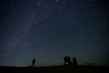 Personas observan las estrellas en el cielo nocturno en las dunas de arena de Erg Chebbi, en el desierto del Sahara, a las afueras de Merzouga (Marruecos) (REUTERS/Darrin Zammit Lupi/Archivo)