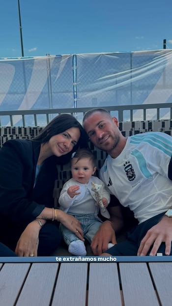 Alexis Mac Allister con una camiseta de Argentina, Ailén Cova y su hija Alaia posan sonrientes para la cámara. La niña lleva un juguete
