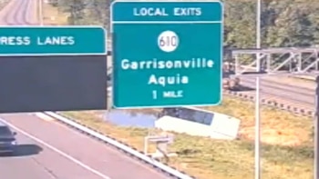 Vista de una autopista con una señal de tráfico verde que muestra "LOCAL EXITS" para Garrisonville y Aquia, y un vehículo en la orilla