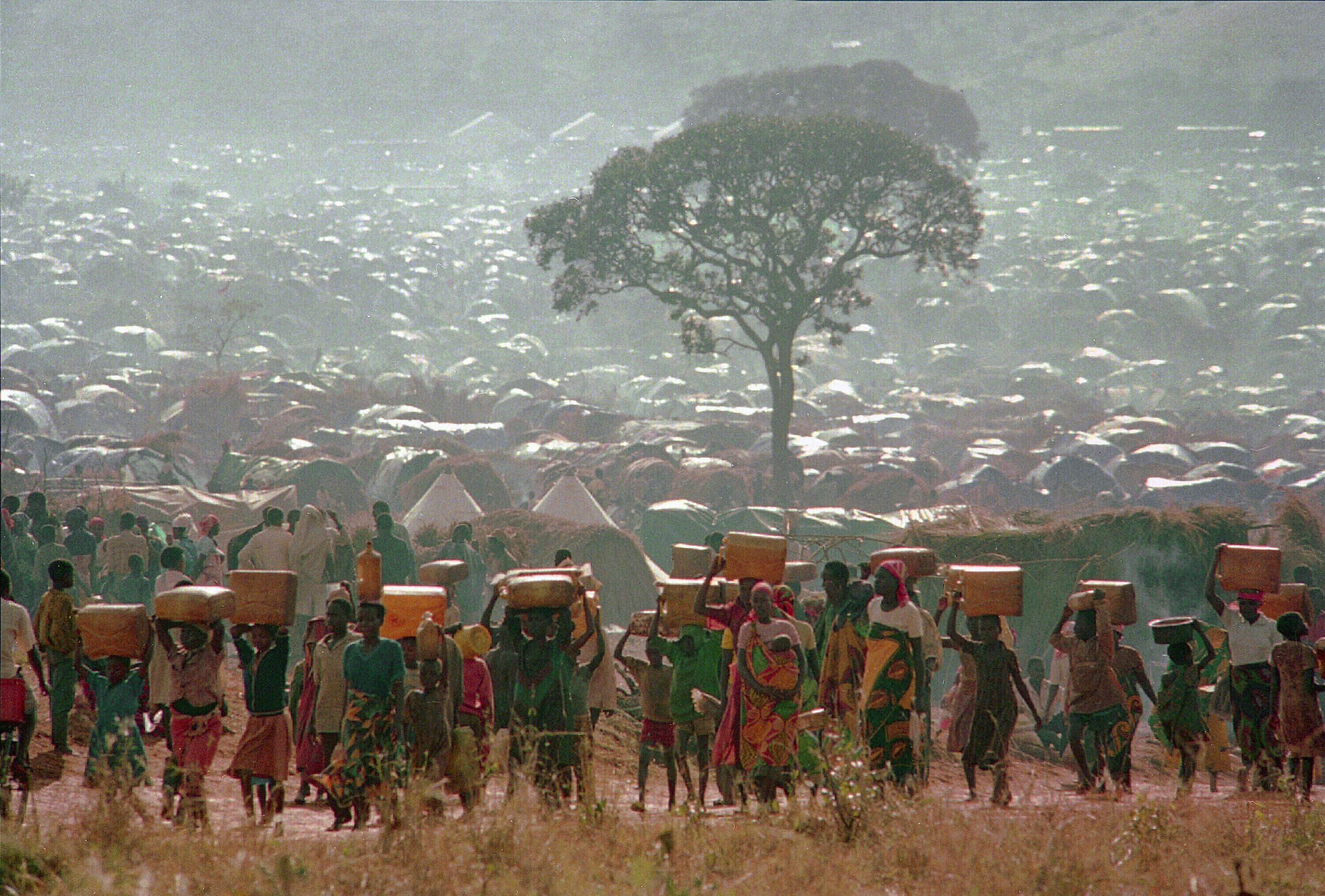 Refugiados, huyendo del conflicto en Ruanda, llevan agua a sus chozas en el campamento de refugiados Benaco en Tanzania, el 17 de mayo del 1994 (AP foto/Karsten Thielker)