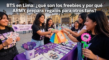 Jóvenes en una plaza pública intercambian bolsas de papel sobre una mesa con tarjetas, distintivos y recuerdos impresos de BTS.