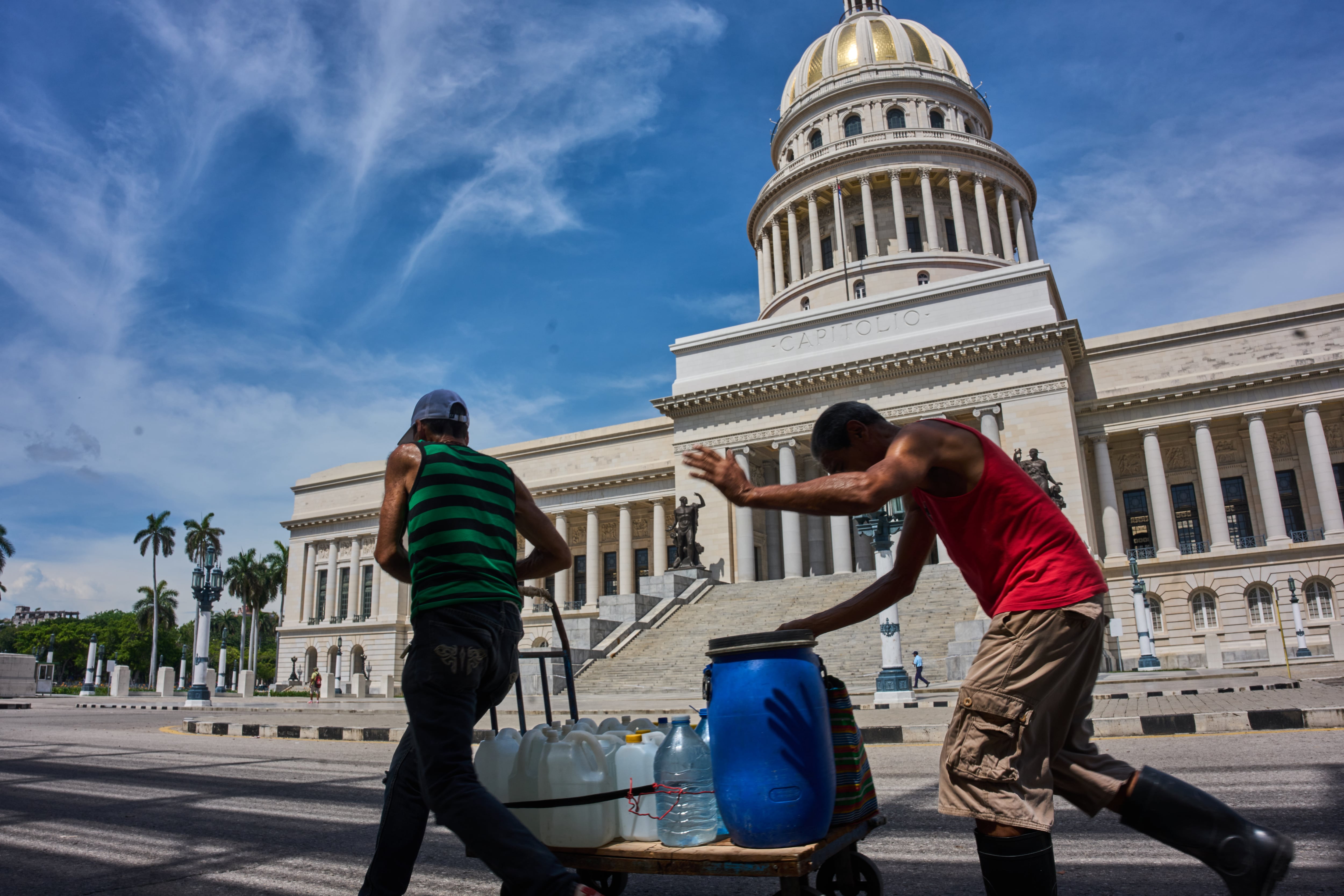 People carry containers of water past the Capitol in Havana, Wednesday, May 27, 2026. (AP Photo/Ramon Espinosa)
