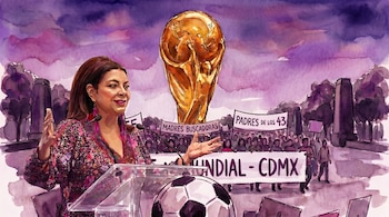 Una mujer habla en un podio con un micrófono, el trofeo de la Copa Mundial, pancartas de "Madres Buscadoras" y "Padres de los 43", y una multitud.