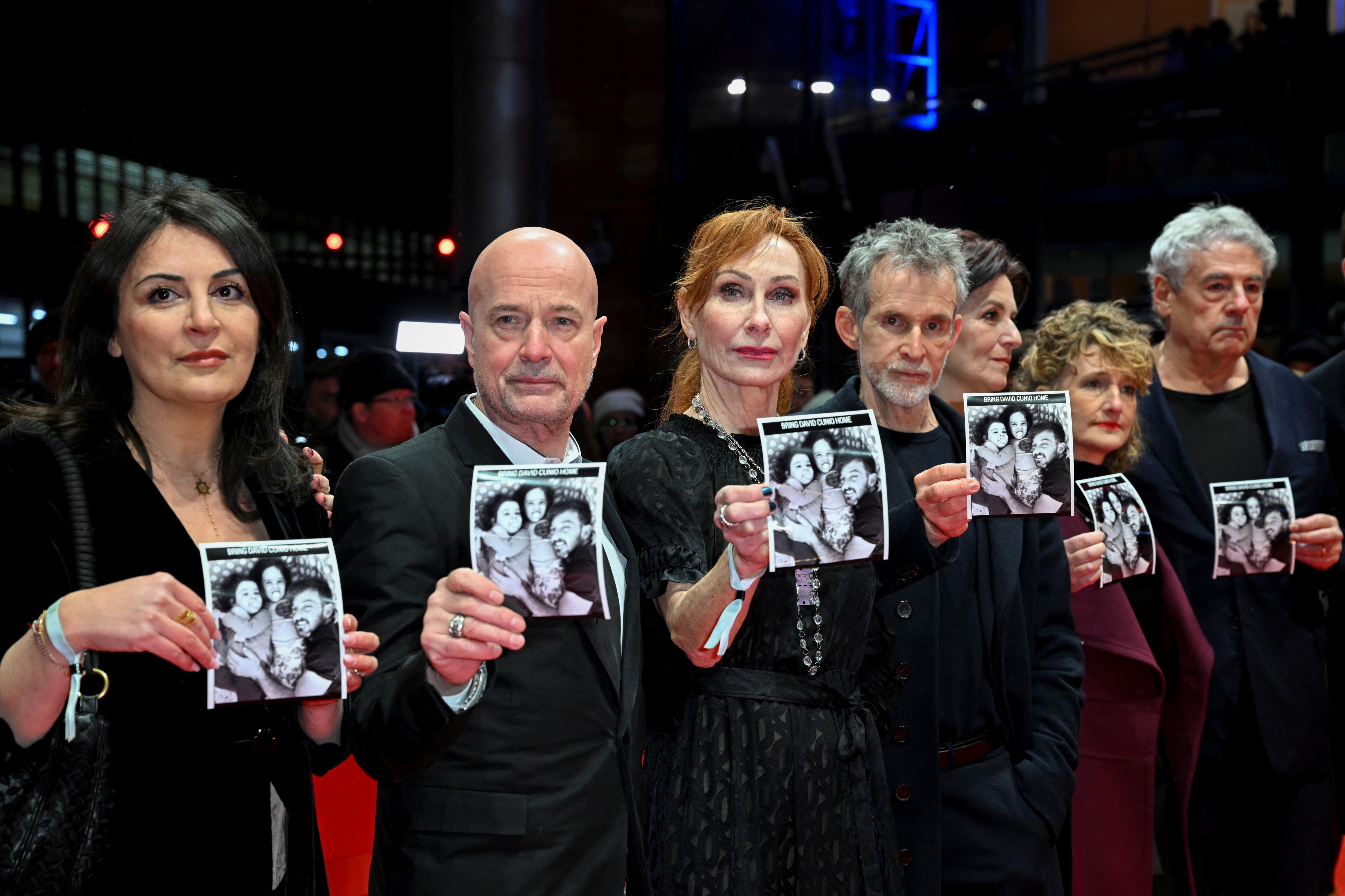 Duzen Tekkal, Christian Berkel, Andrea Sawatzki, Ulrich Matthes y Tricia Tuttle (con abrigo rojo) sostienen fotos del rehén israelí David Cunio en la alfombra roja de la gala inaugural de la 75° Berlinale. Berlín, 13 de febrero de 2025 (REUTERS/Annegret Hilse)