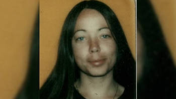 Primer plano de una mujer joven con cabello oscuro y largo, ojos claros, y una ligera sonrisa, sobre un fondo liso de color ocre claro