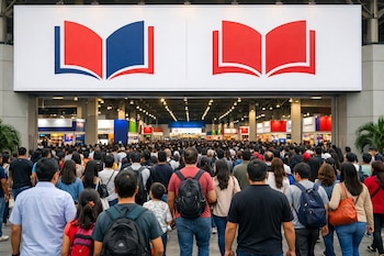 Una multitud de personas entra a un recinto. Arriba, dos grandes logos de libros abiertos, uno rojo y azul y el otro rojo. Al fondo se aprecian stands.