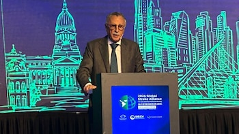 Hombre mayor con traje y gafas habla en un podio. Detrás, una pantalla azul muestra '2026 Global Stroke Alliance' y siluetas de edificios verdes
