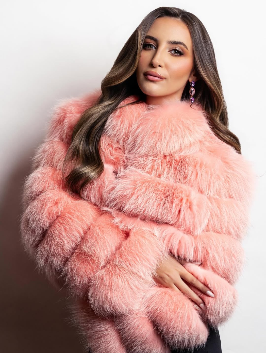 Viste un tapado rosa salmón de piel sintética y pendientes violetas, sumando volumen y color en una estética “Mob Wife” renovada (Instagram: @abruduhalde)