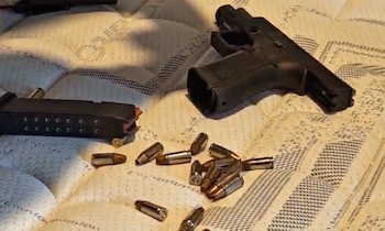 Una escopeta, un subfusil, dos pistolas, cargadores y diversos cartuchos y balas ordenados sobre una mesa de madera