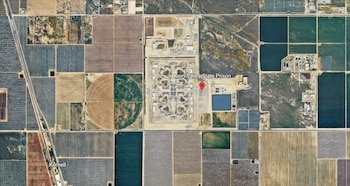Vista aérea por satélite de un complejo penitenciario con un marcador rojo y la etiqueta Kern Valley State Prison, rodeado de campos agrícolas