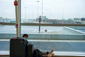 Un pasajero se sienta con su equipaje en el aeropuerto internacional John F. Kennedy después de que las aerolíneas anunciaran la cancelación de numerosos vuelos (Reuters)