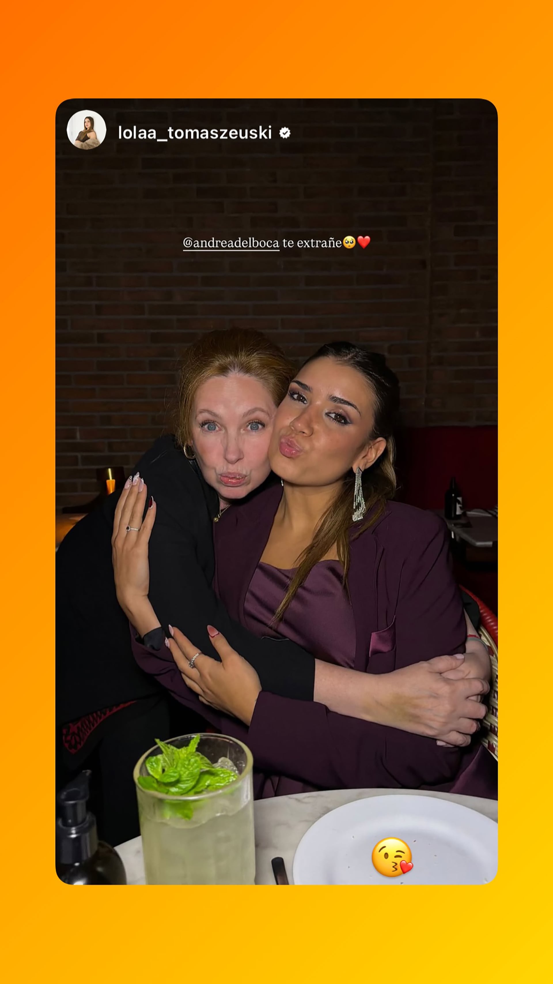 Lola Tomaszeuski y Andrea del Boca se abrazan cariñosamente, compartiendo un momento de alegría con una caipirinha sin alcohol sobre la mesa.