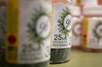 Primer plano de dos frascos de gomitas Greenbelt Botanicals con etiquetas que indican 25 mg de Delta 8 THC, con más frascos al fondo