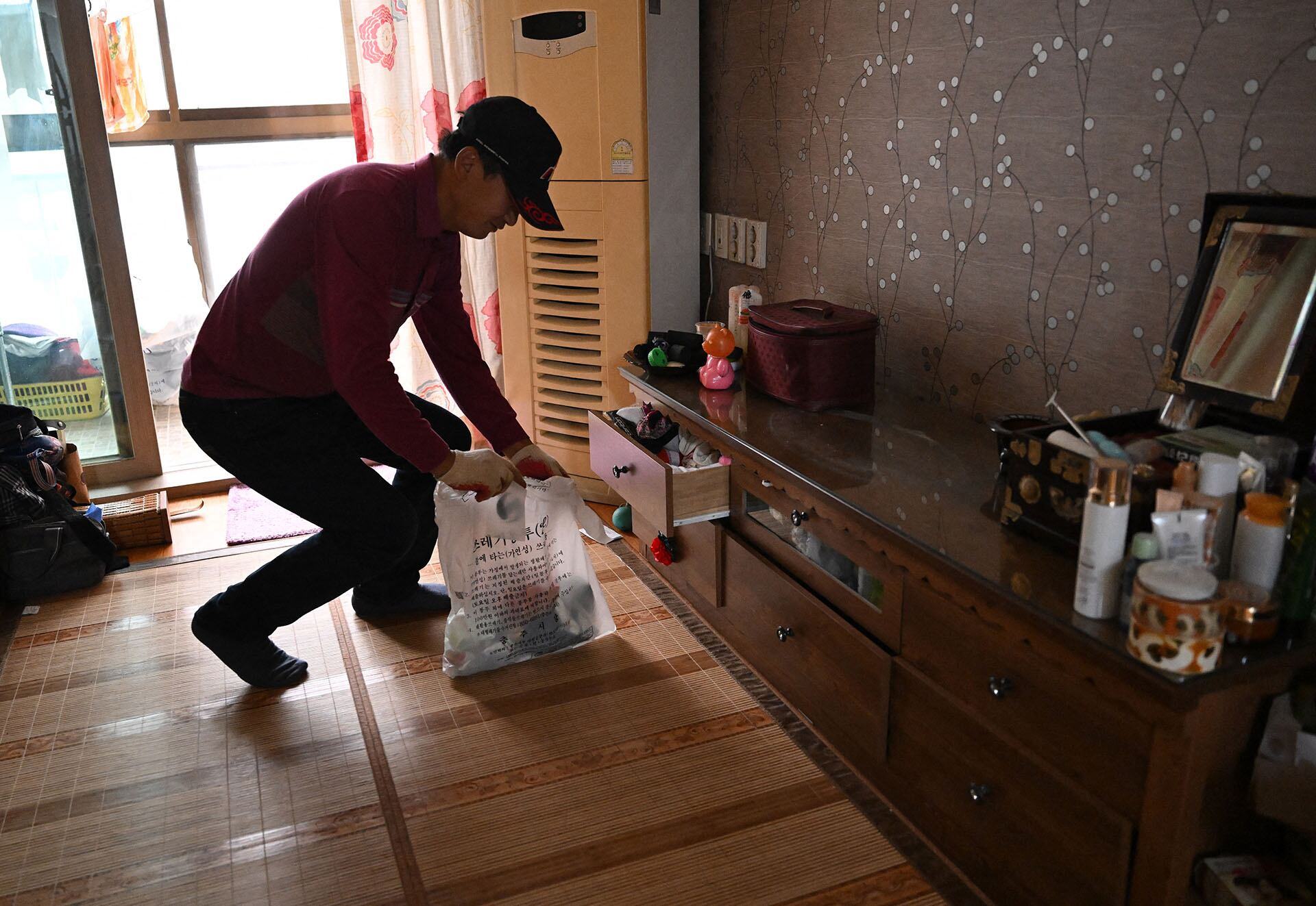 Kim Seok-jung, una limpiadora que acondiciona casas tras el fallecimiento de sus ocupantes —a menudo personas que vivían solas—, limpia la habitación de una mujer de casi 90 años que había fallecido recientemente en Chungju. (Foto de Jung Yeon-je / AFP)