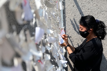 Una mujer coloca un mensaje dedicado a seres queridos y personas fallecidas a causa de la covid-19, en un mural improvisado en la Basílica de Guadalupe, en la Ciudad de México (México). EFE/Sáshenka Gutiérrez