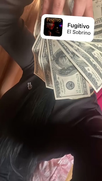 Una mano sostiene varios billetes de cien dólares dispuestos en abanico junto a un recuadro de música con el título Fugitivo de El Sobrino