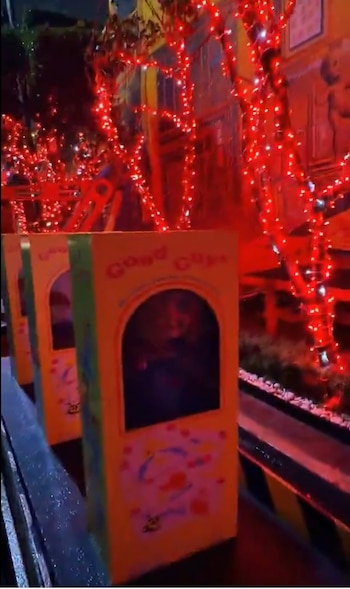 Tres cajas amarillas con la marca Good Guys alineadas de noche junto a árboles cubiertos de luces rojas