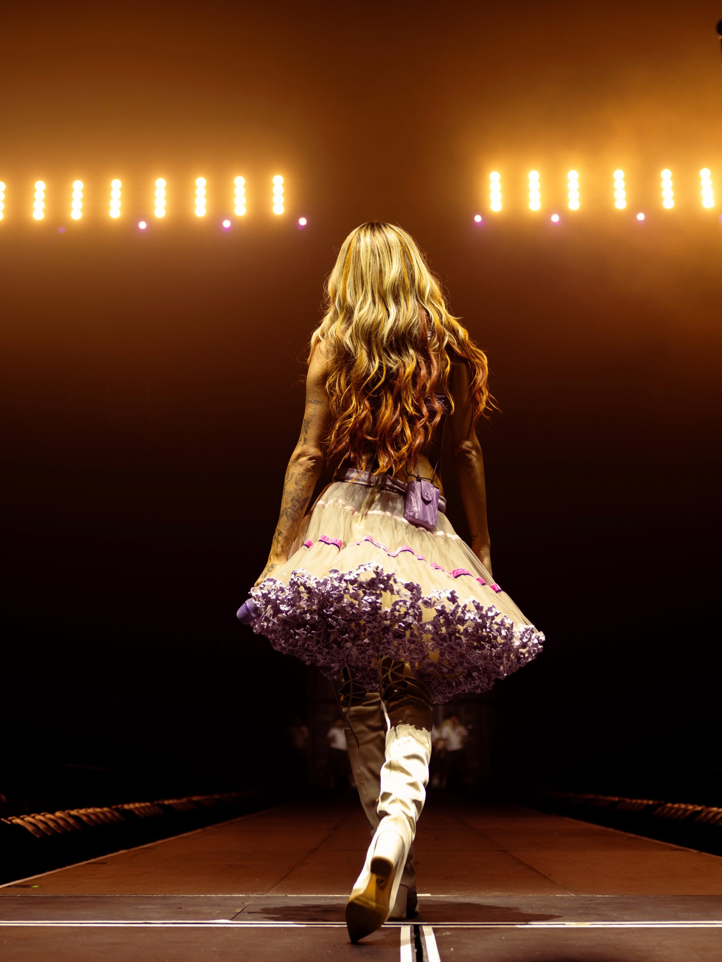 Con un look inspirado en sus días en Violetta, Tini apareció de espaldas frente a una fila de luces, con un vestido claro y una falda amplia