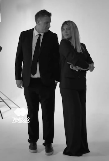 Fotografía en blanco y negro de Wanda Nara y Maxi López, ambos de pie con trajes formales oscuros. Él la mira y ella tiene los brazos cruzados