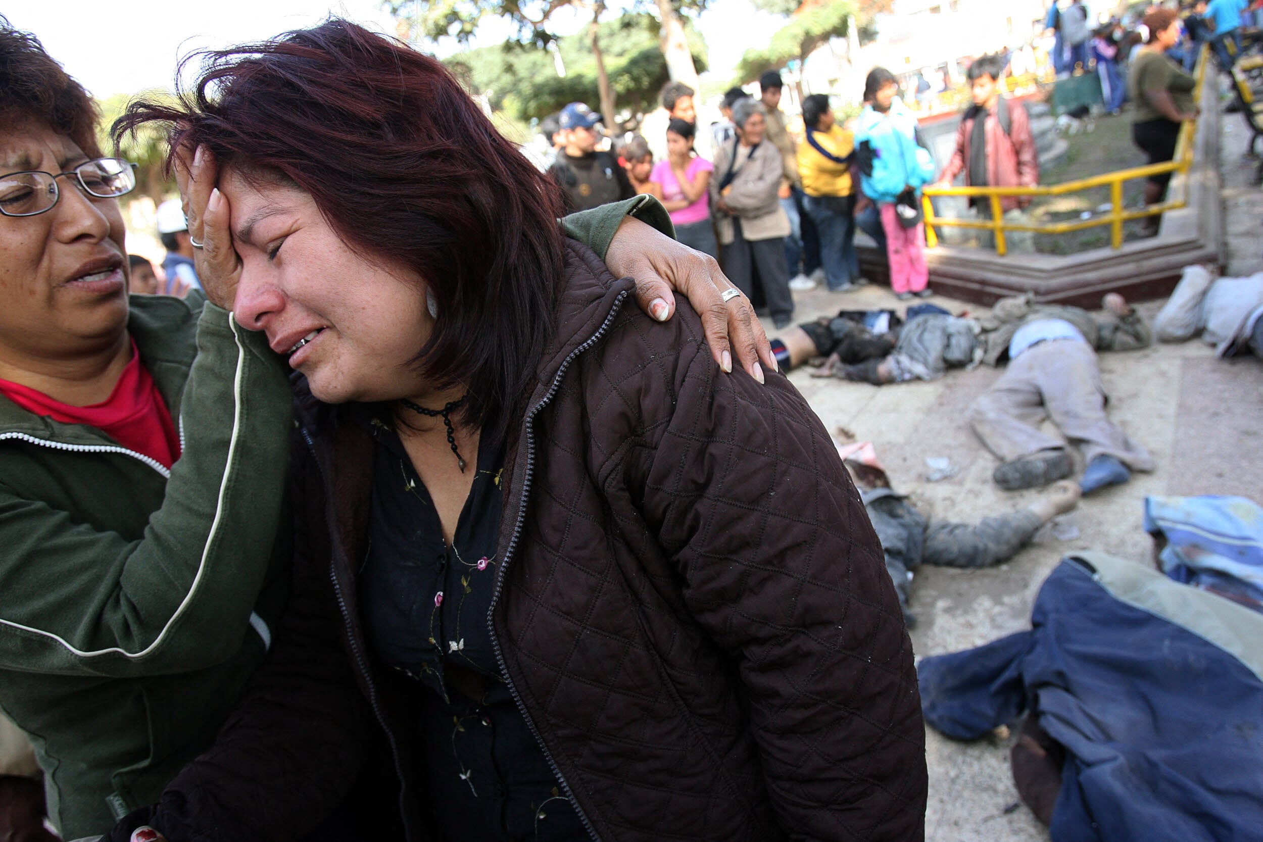 A woman comforts another who broke in tears after identifying the corpse of a relative killed by the earthquake that hit a large area of Peru in the eve 16 August, 2007 in Pisco, more than 300 km south from Lima. Peruvian officials struggled on Thursday to reach cut-off victims on the country's southern coast after a devastating earthquake rocked the region leaving more than 500 dead and 1,050 injured. AFP PHOTO / JAIME RAZURI (Photo by JAIME RAZURI / AFP)