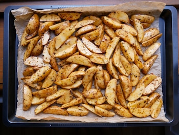 Patatas gajo crujientes asadas y sazonadas con hierbas, presentadas en una bandeja para hornear listas para servir.