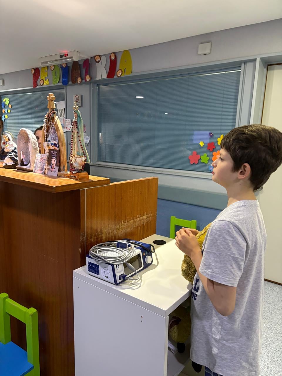 Antonio Ventura permanece de pie frente a un altar con imágenes religiosas en el área de pediatría durante su proceso de recuperación