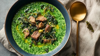 Papilla verde de hojas cocidas con carne de res troceada encima, servida en plato hondo sobre fondo neutro. – (Imagen Ilustrativa Infobae)