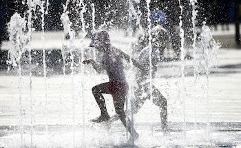 Niños se refrescan bajo una