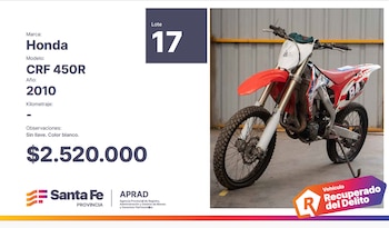 Una motocicleta Honda CRF 450R enduro roja y blanca con el número 84, modelo 2010, estacionada sobre un suelo de concreto en un almacén