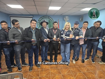Nueve personas adultas cortan una cinta azul con tijeras en una sala con paredes azules. Un logo circular de la Junta Directiva de 48 Cantones es visible en la pared
