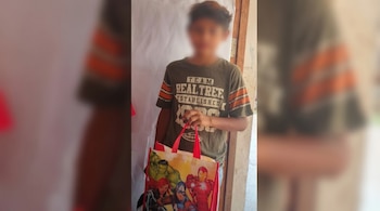 Un niño con el rostro difuminado viste una camiseta verde y naranja, sosteniendo una bolsa reutilizable blanca y roja con ilustraciones de los personajes de Marvel.