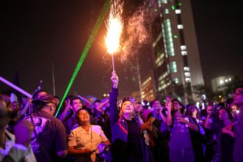 Una mujer sostiene una bengala mientras otras miran poco antes de celebrar el año nuevo en Plaza Italia durante una protesta contra el gobierno de Chile en Santiago, Chile, el 31 de diciembre de 2019. (REUTERS / Pablo Sanhueza)