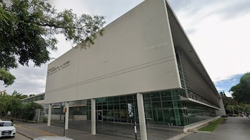 Fachada de un edificio blanco con grandes ventanales de vidrio, columnas y la inscripción del Hospital Clemente Álvarez
