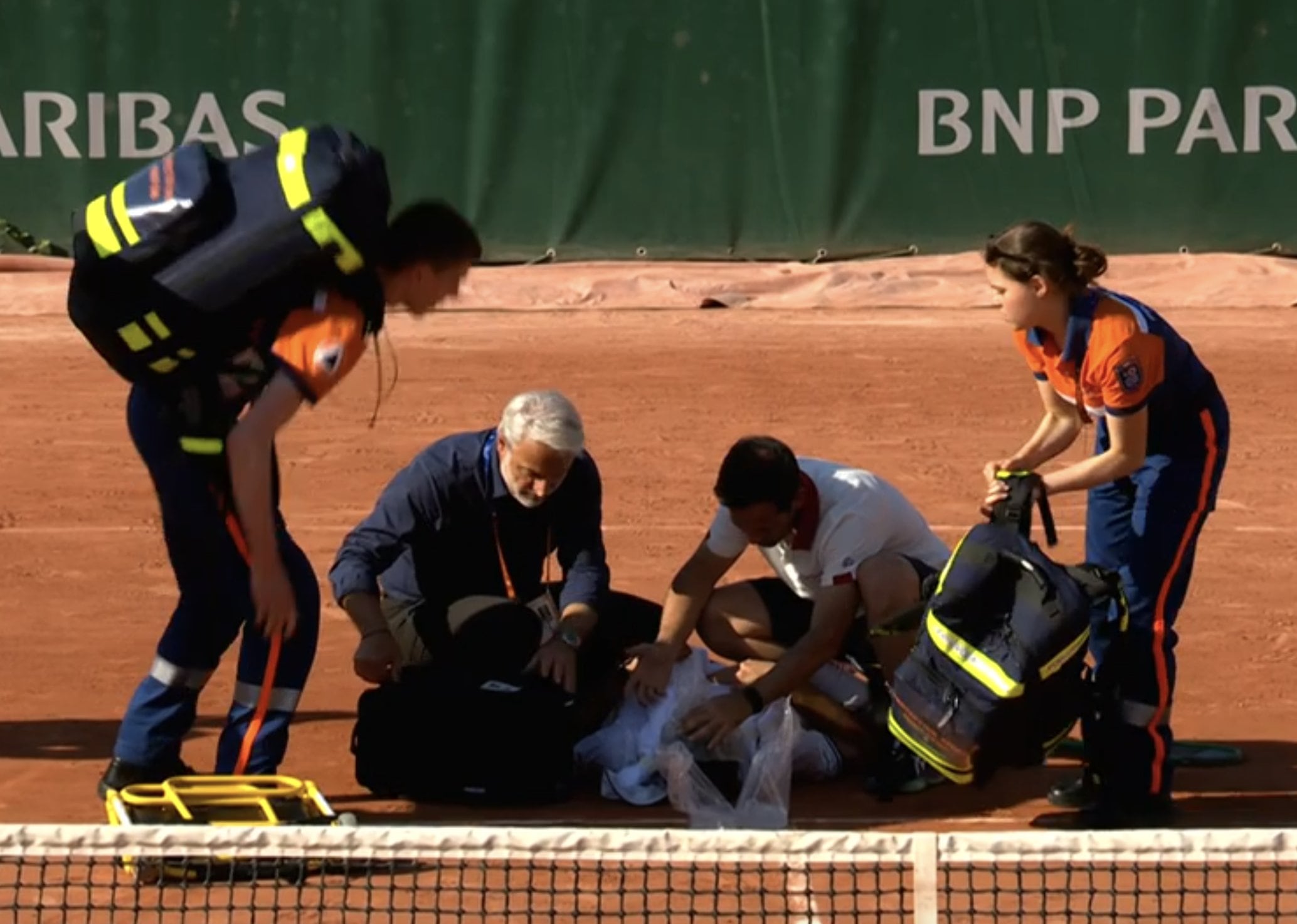 Jakub Mensik recibe asistencia médica en la cancha de Roland Garros tras colapsar por agotamiento al ganar un partido de casi cinco horas contra Mariano Navone (Crédito: ESPN)