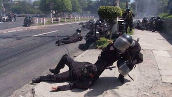 Agentes de la Unidad de Mantenimiento del Orden buscan refugio tras los disparos frente a la Universidad de El Salvador, durante la protesta del 5 de julio de 2006 (Cortesía EDH).
