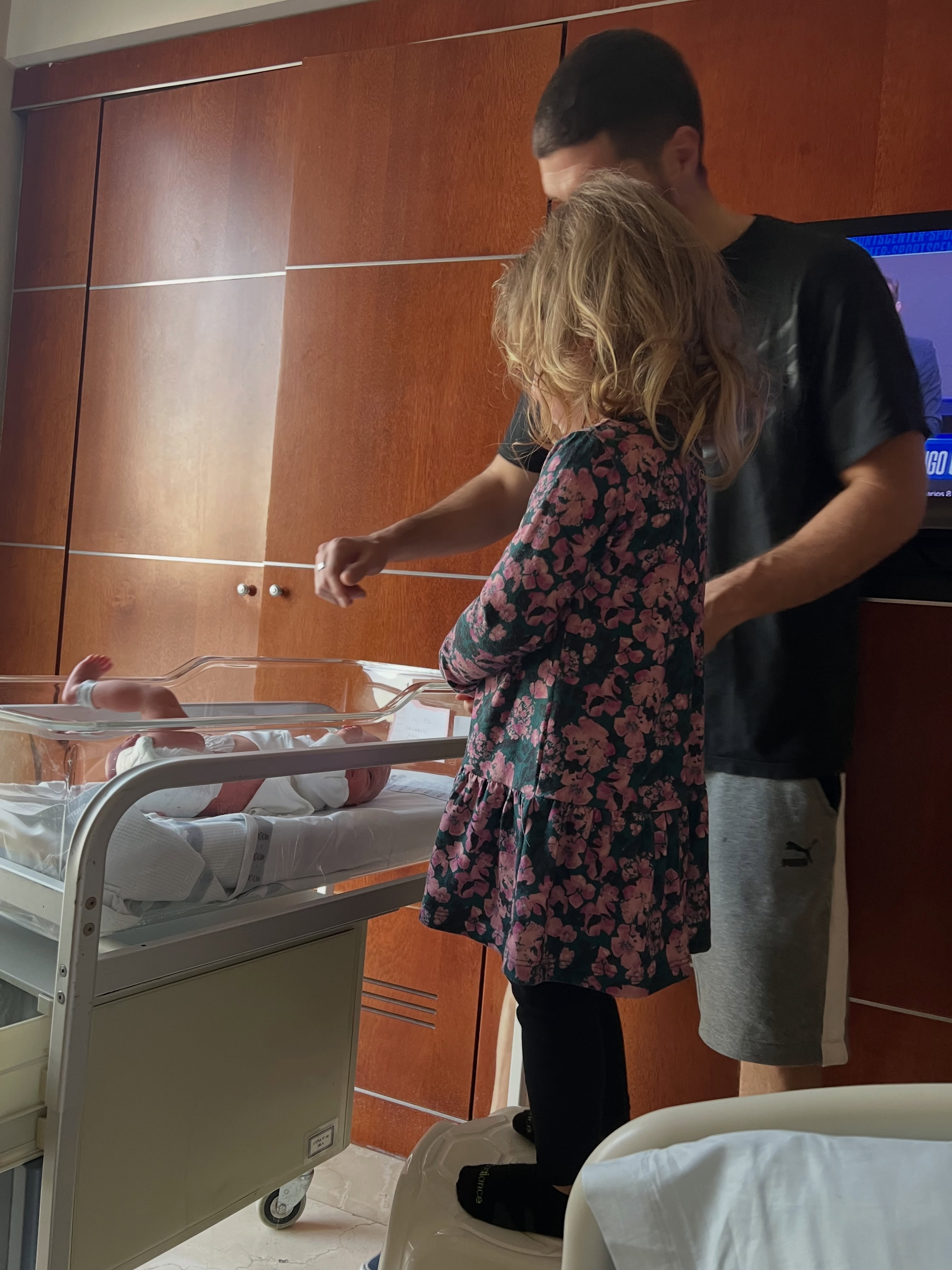 Roma, hija de Dalma Maradona, observa a su hermana recién nacida en la cuna transparente de un hospital, acompañada por su padre Andrés Caldarelli