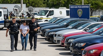 Una mujer esposada es escoltada