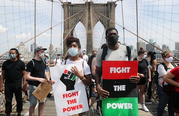 Manifestantes sostienen pancartas en el Puente de Brooklyn en solidaridad con los familiares de George Floyd en Nueva York este 6 de junio de 2020 (REUTERS/Jeenah Moon)