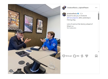 Flavio Briatore, de gorra y gafas, gesticula mientras habla con Franco Colapinto, con chaqueta azul, sentados en una mesa de reuniones con dispositivos electrónicos