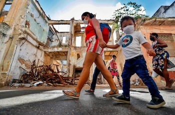 Varias personas caminan por la calle usando mascarillas para protegerse del coronavirus en La Habana (CUBA).