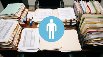 Mesa de trabajo con pilas de carpetas de documentos de varios colores, papeles sueltos, sellos de tinta, un bolígrafo y el logo de un glifo humano blanco en círculo azul.