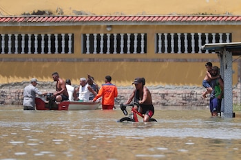 Habitantes transitan hoy por una calle inundada tras las lluvias de los últimos dos días, en el municipio de Duque de Caxias, en la región Baixada Fluminense, área metropolitana de Río de Janeiro (Brasil). EFE/ André Coelho