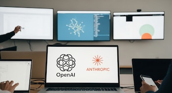 Vista de una oficina moderna con pantallas de inteligencia artificial, laptops abiertas y manos interactuando. Los logos de OpenAI y Anthropic son visibles en una pantalla.