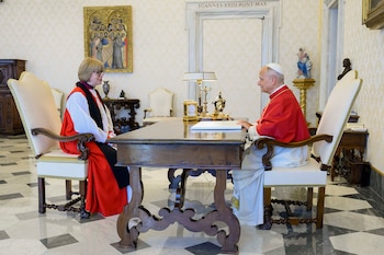 León XIV, vestido de rojo, y Sarah Mullally, con atuendo clerical, sentados uno frente al otro en un escritorio de madera en una sala formal
