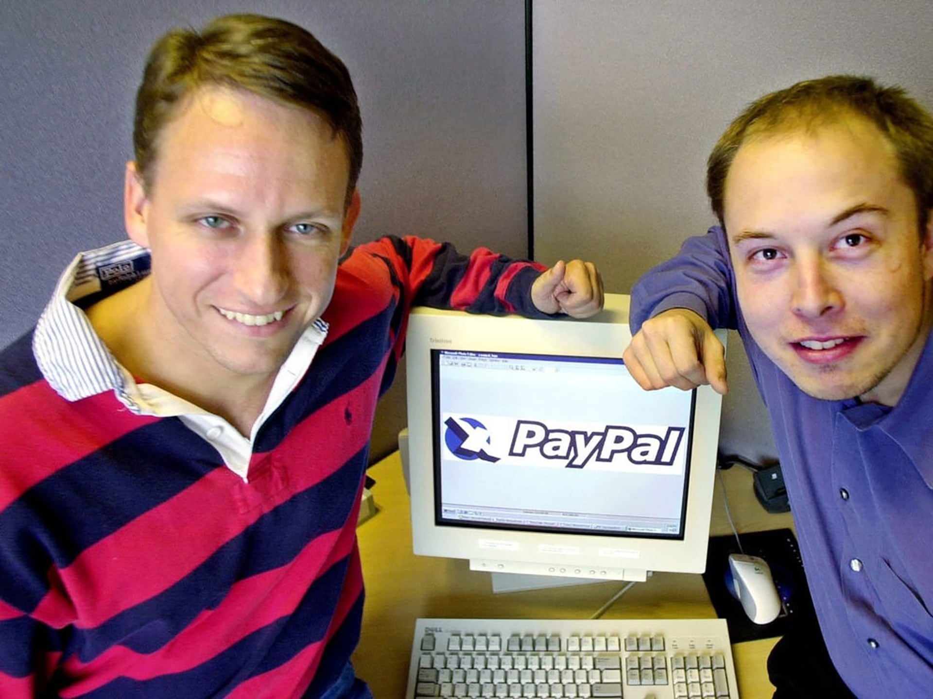 Peter Thiel y Elon Musk posan junto a un monitor con el logo de PayPal, marcando los inicios de la influyente empresa de pagos en línea