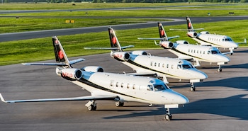 Cuatro aviones blancos y negros con la estrella de la vida alineados en la pista de un aeropuerto