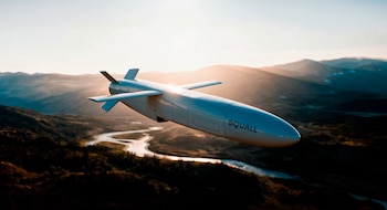 Misil de color claro con la palabra Squall impresa en el fuselaje en vuelo sobre montañas y un río iluminados por el sol