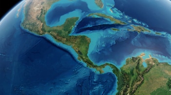 Vista de satélite de Centroamérica, el Mar Caribe y las islas. Se ven masas de tierra con vegetación y montañas, junto con océanos profundos y aguas costeras claras.