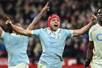 Louis Bielle-Biarrey, jugador de rugby francés, con un gorro protector rojo y camiseta azul claro, celebra con los brazos abiertos y la boca abierta